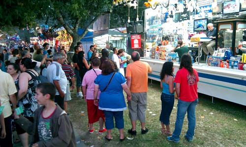 La gente viendo el partido en la pantalla de una tómbola en las fiesta de Coia.