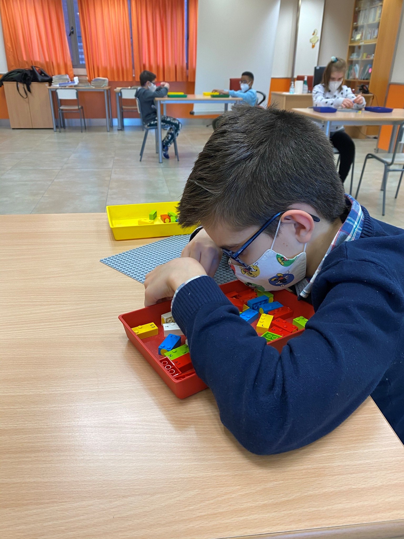 Grupo de escolares jugando en el aula con las piezas de LEGO Braille